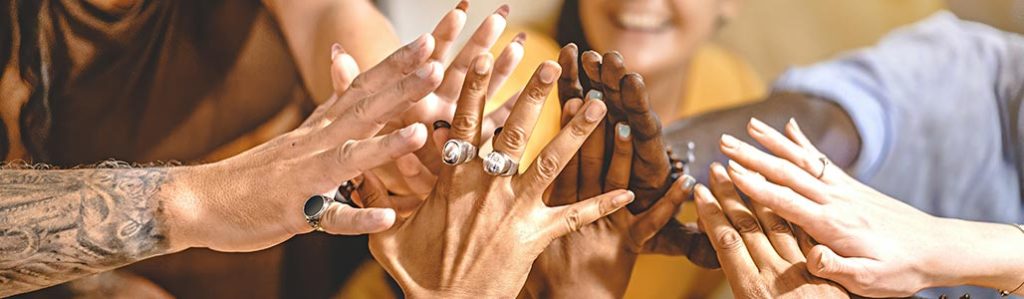 Photo demonstrating people in long term sober living communities putting their hands together to celebrate their sobriety.